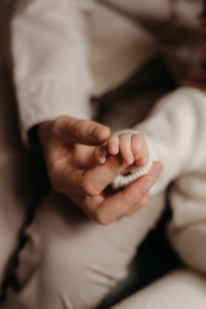Picture of four month old babies hand and Dad hand during family photo shoot at Home