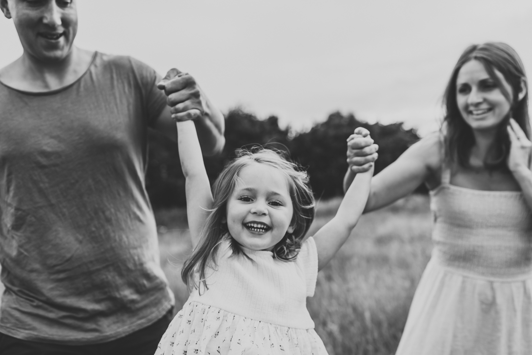 black and white images of girl being swung by her parents