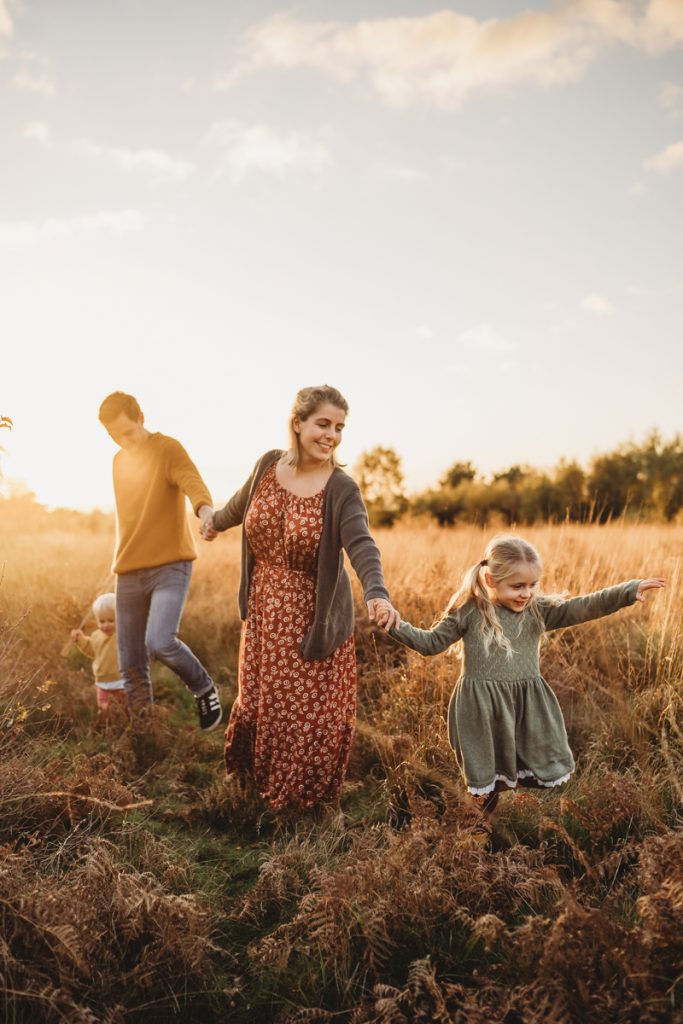 Family being lead through a field at sunset wearing beautiful clothes i long grass 