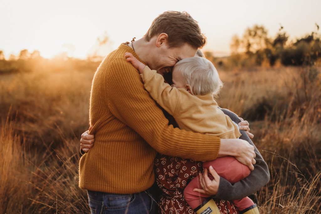 Family having a cuddle in the sunset and golden grass is in Hampshire