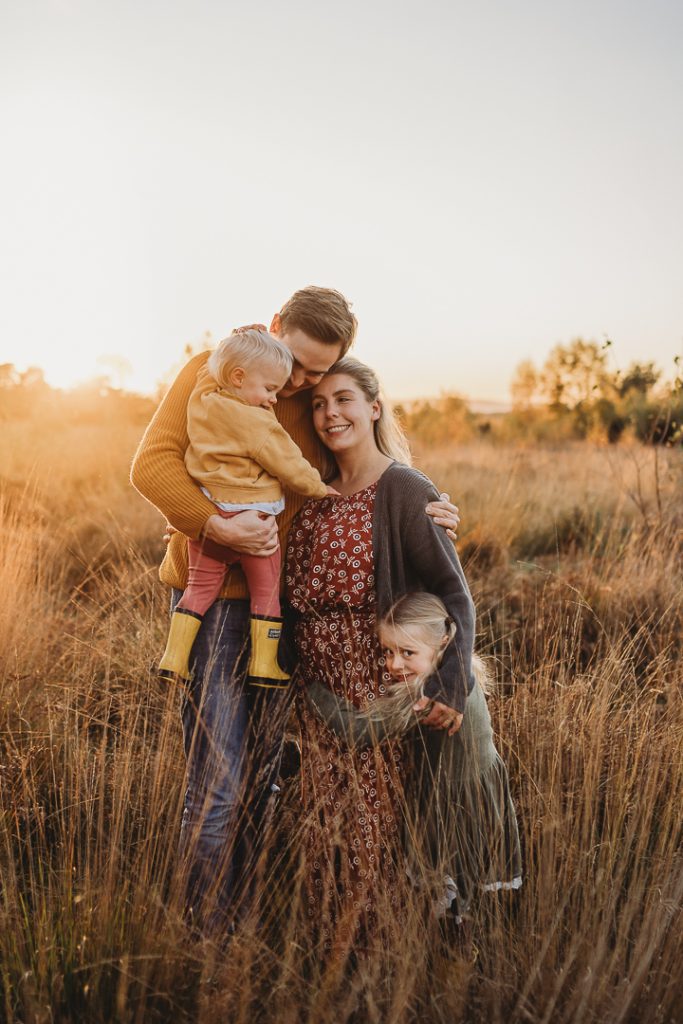 family cuddles at golden hour in a field