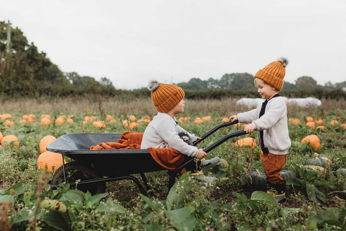 kids riding in a wheelbarrow on sunnyfields pumpkin farm