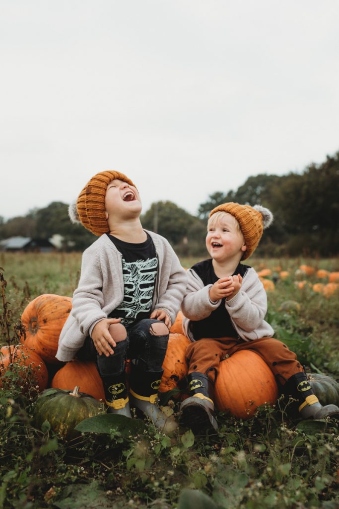 kids sitting on pumpkins laughing at sunnyfileds farm