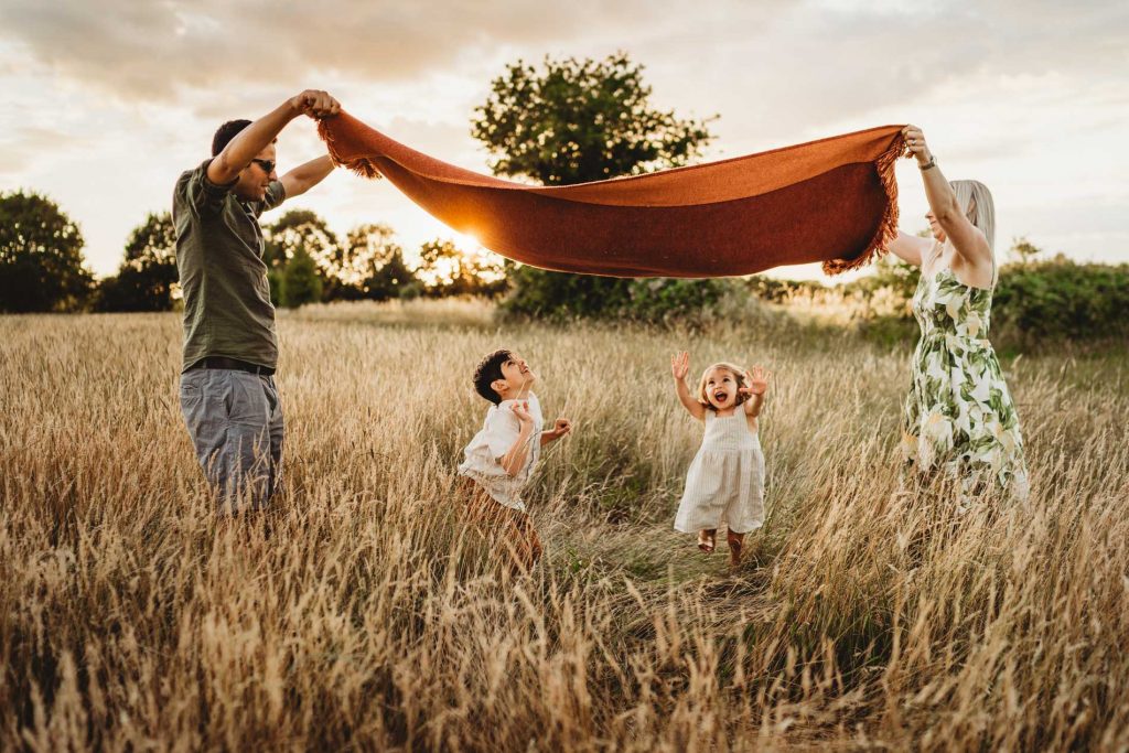 family playing under s blanket in the long grass at sunset 