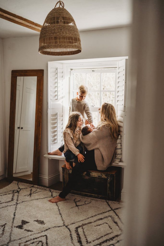 newborn baby with mum and siblings in window relaxed newborn photography hampshire