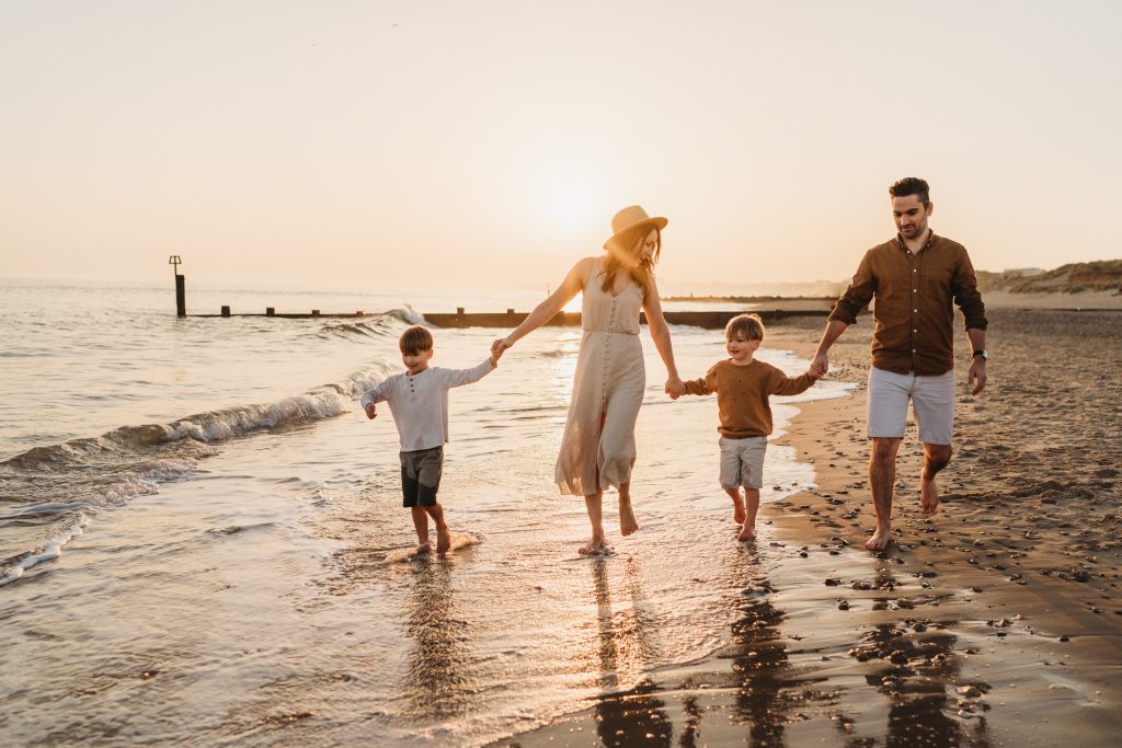 family walking along the beach holding hands at sunset 