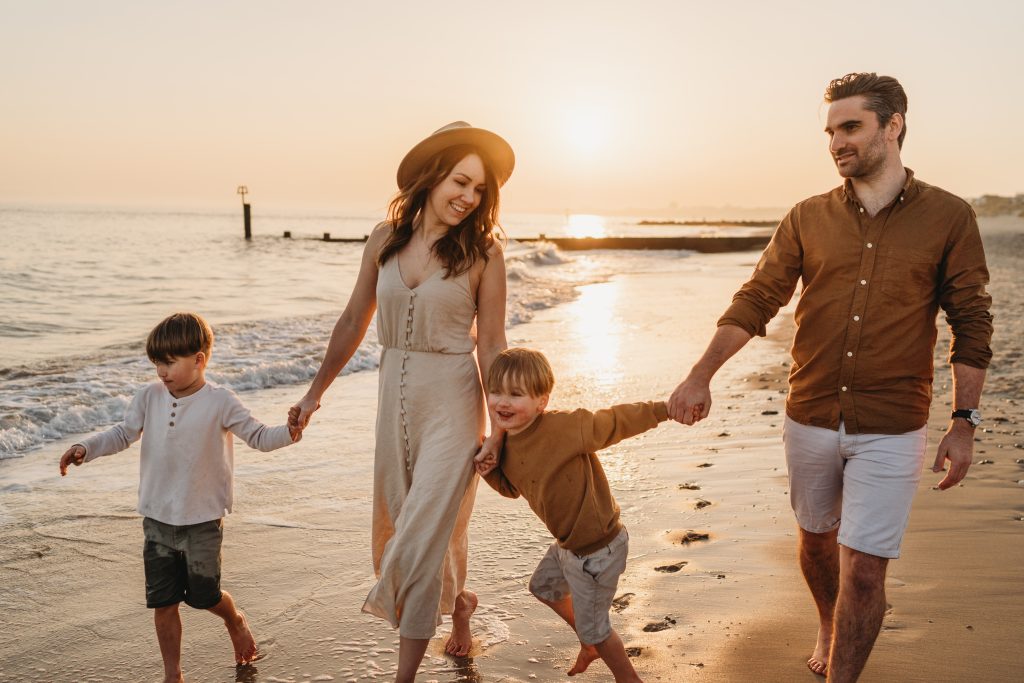 Family walking hand-in-hand along the beach at sunset