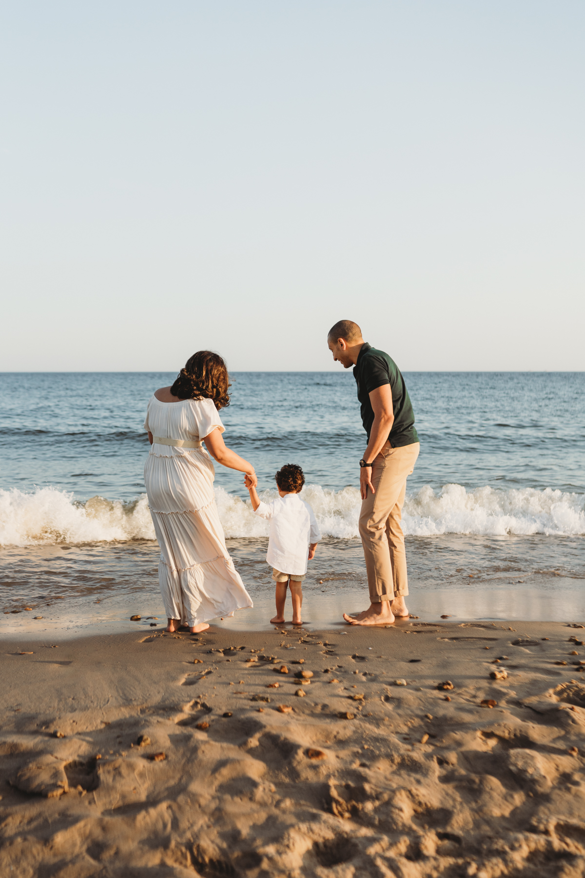 Family standing on waters edge at the beach
