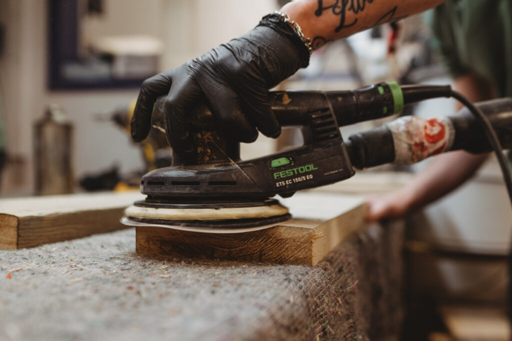a close up image of a man sanding wood with a sander