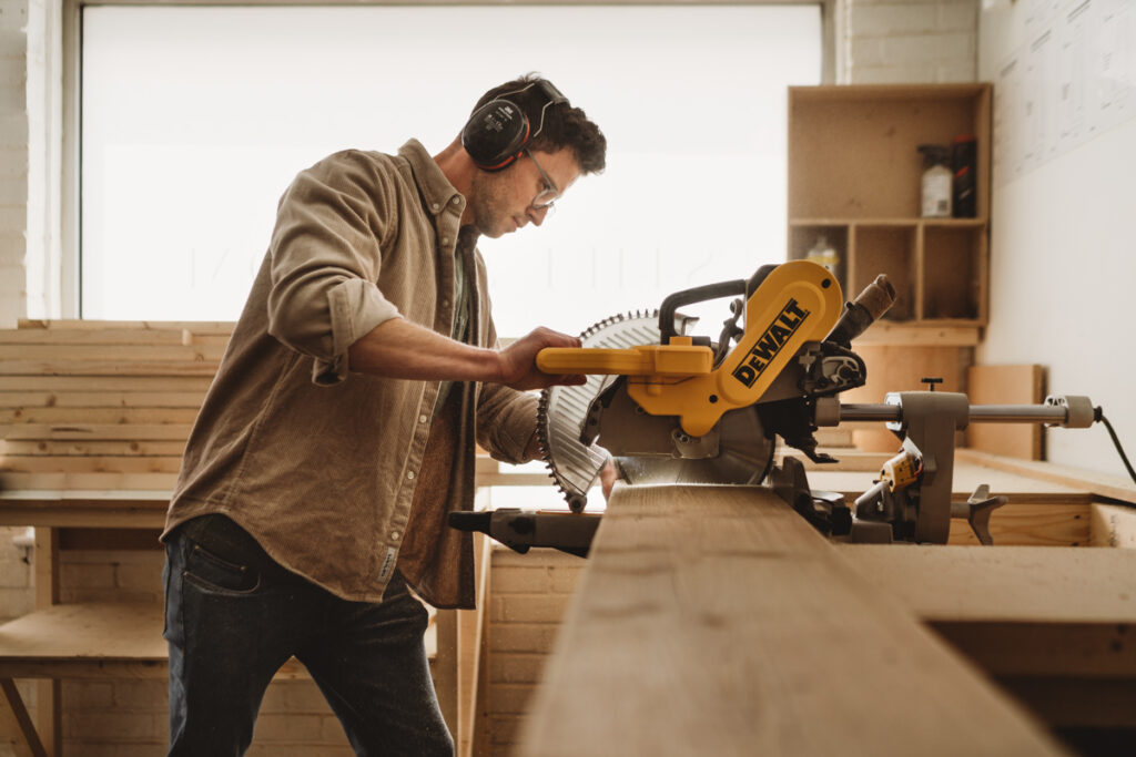 a man cutting some reclaimed wood on a circular saw on a photoshoot for the still and bloom brand 