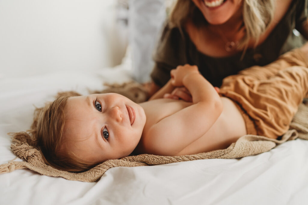 little boy playing on the bed with mum at home during a photoshoot