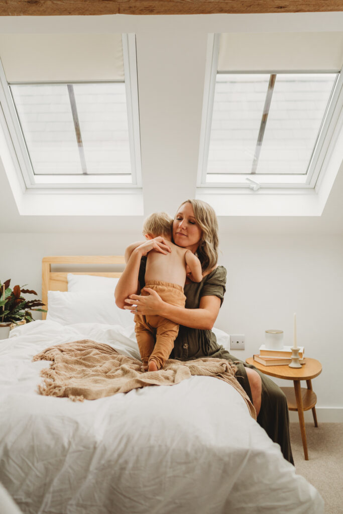 mum and son cuddle on the bed at home.  At-Home Photoshoot London