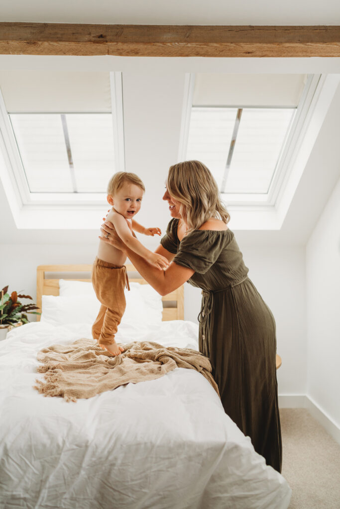 little boy jumping on the bed with mum at home 