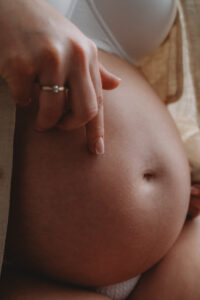 close up of a pregancy belly with mum tracing her finger over the bump