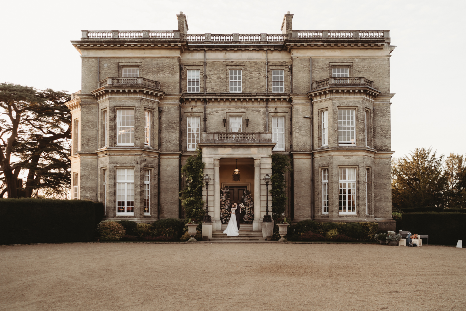 Wide shoot Picture of Hedsor house maidenhead, with the wedding couple standing in the doorway with flowers behind